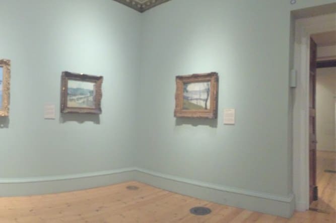 Pared de museo con obras enmarcadas junto a una puerta numerada
